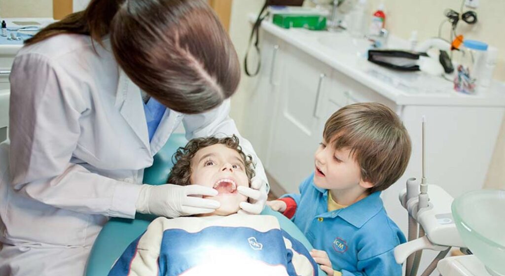 Dentista inspeccionando a un niño